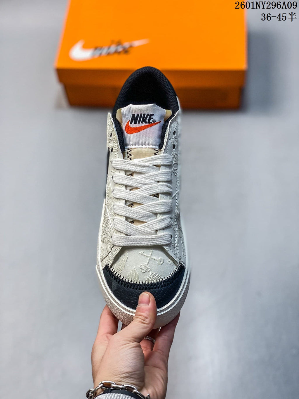 Top view of one sneaker showing white laces, an orange-accented Nike tongue label, embossed upper details, and a black textured toe panel.