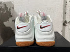 Rear view of white Nike Foamposite sneakers with red-and-green heel Swooshes and gum-colored outsoles