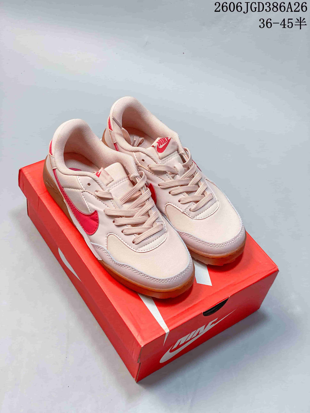 Pair of pale pink and red Nike Terra Manta Suede sneakers displayed on a red Nike shoebox; image text shows style code 2606JGD386A26 and size range 36–45.5.