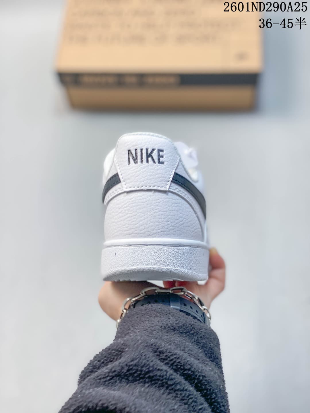Rear view of a white Nike sneaker with a dark navy heel stripe and Nike branding.