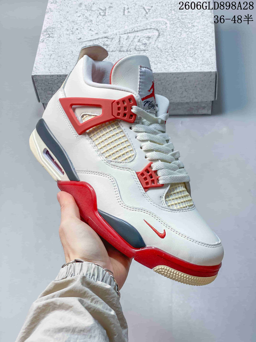 Angled side view of the white sneaker with red and grey accents and cream-toned outsole details.