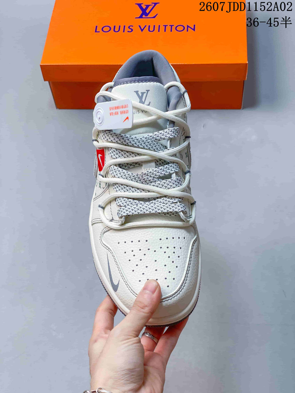 Top view of a white low-top sneaker showing perforations, layered laces, and gray accents.
