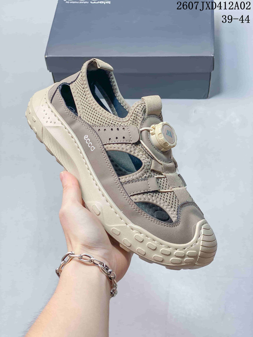 Side view of a taupe ECCO closed-toe sandal showing open side panels, dial-style closure, and textured sole.