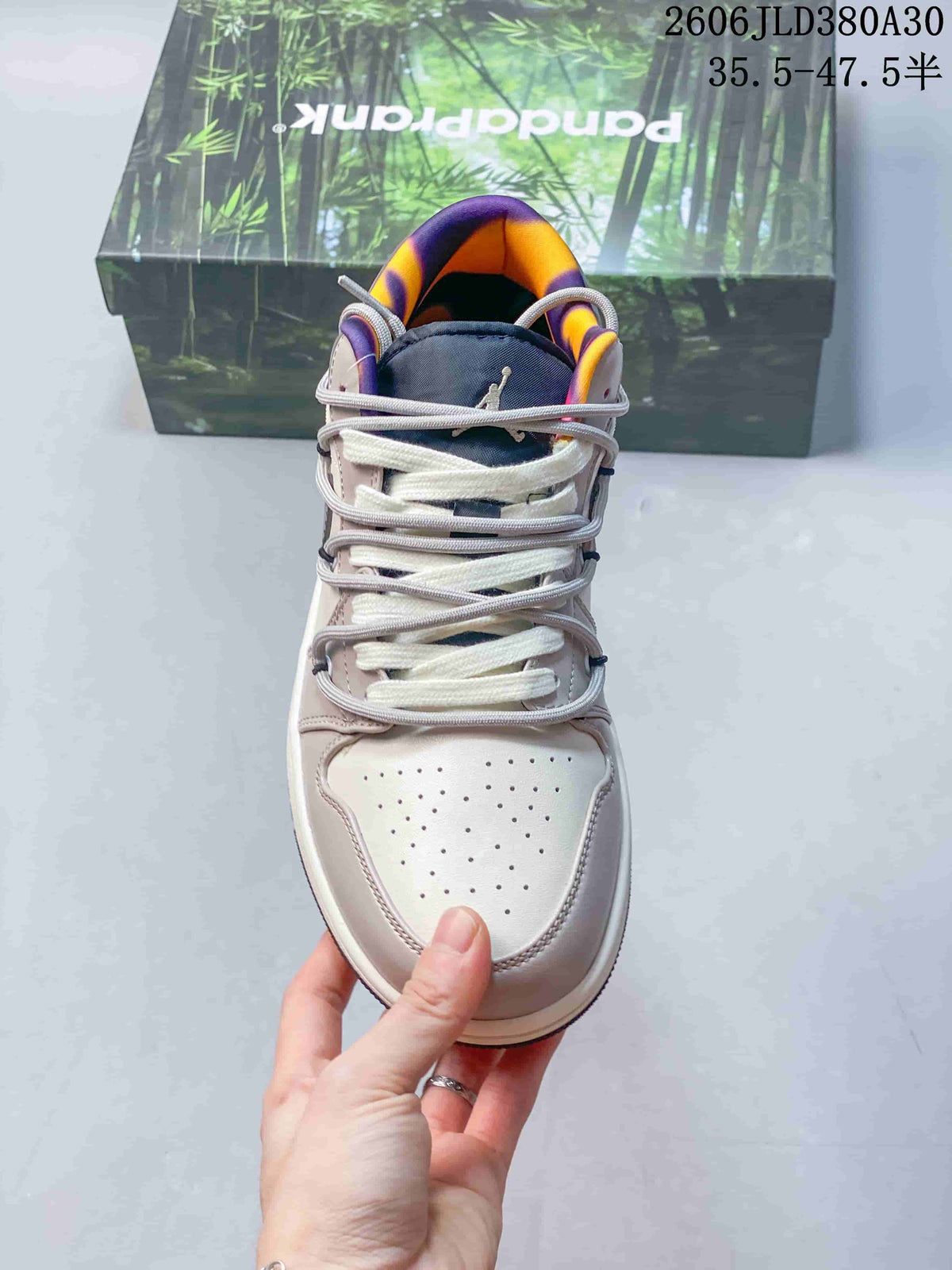 Front view showing the perforated toe, layered laces, and purple and orange collar lining.