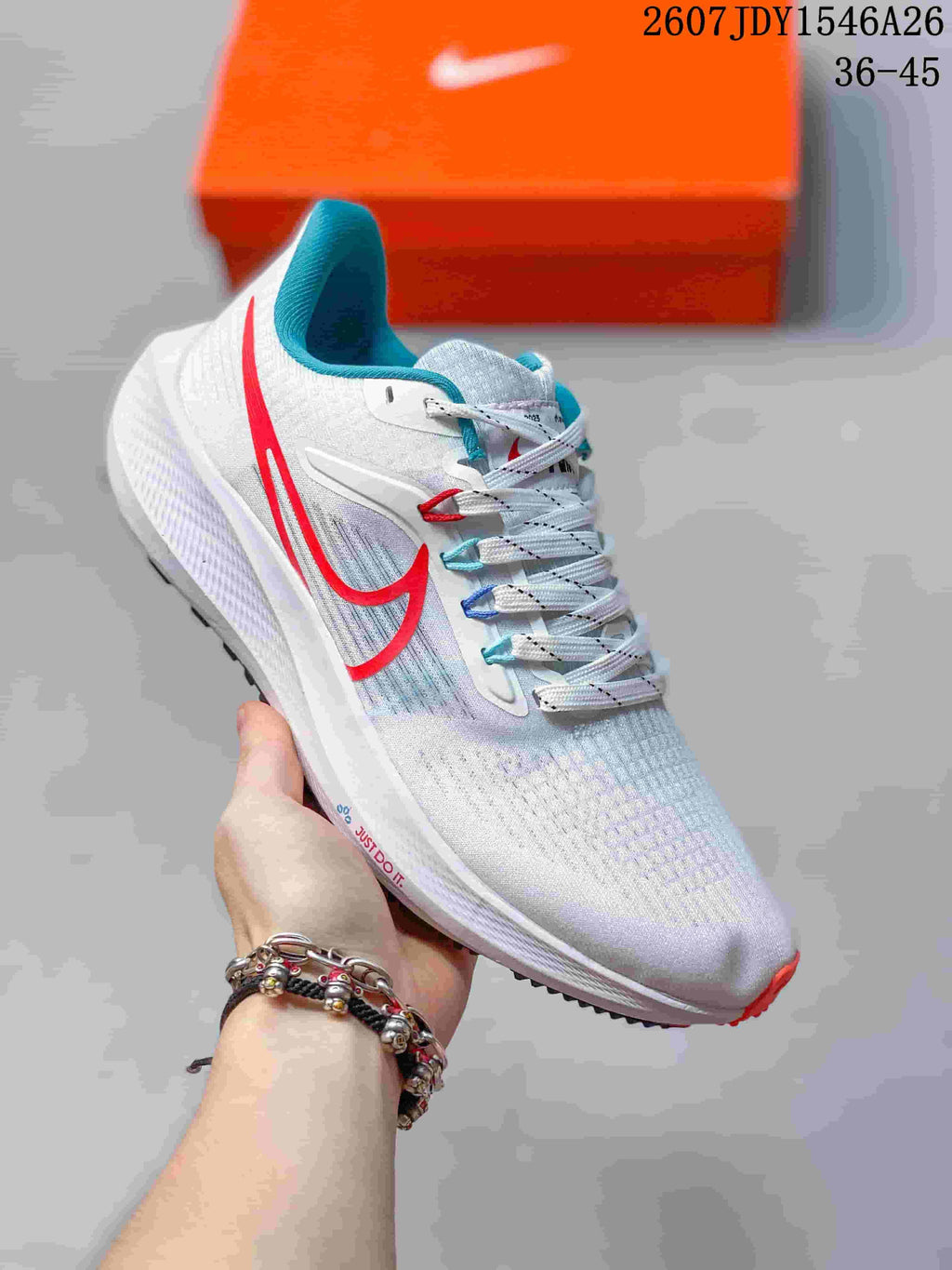 White Nike Air Zoom Pegasus 39 sneaker with red and blue accents, shown from the side with an orange shoe box behind it.