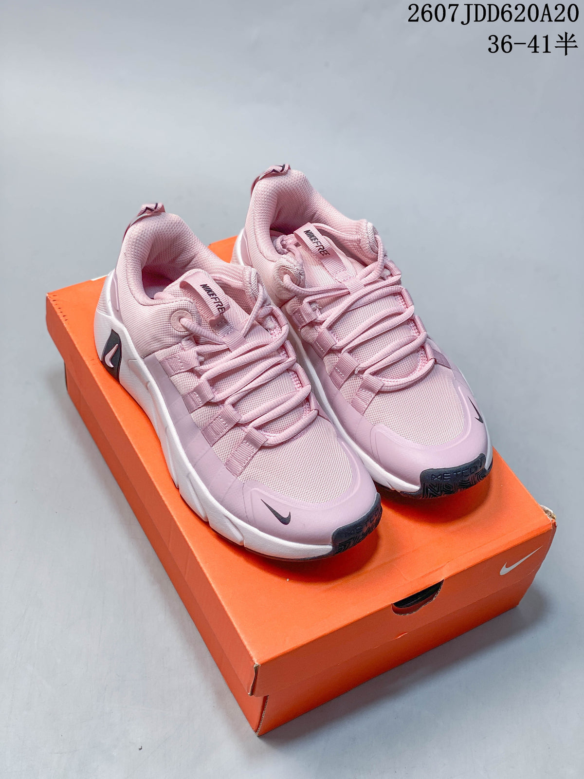 Pair of pink and white Nike Free Metcon 7 training shoes displayed on an orange shoebox; style code 2607JDD620A20 and size text are visible above.