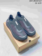 Pair of dark gray DESCENTE PRIMER slip-on sneakers displayed on a shoebox, with the style code and size range shown above.