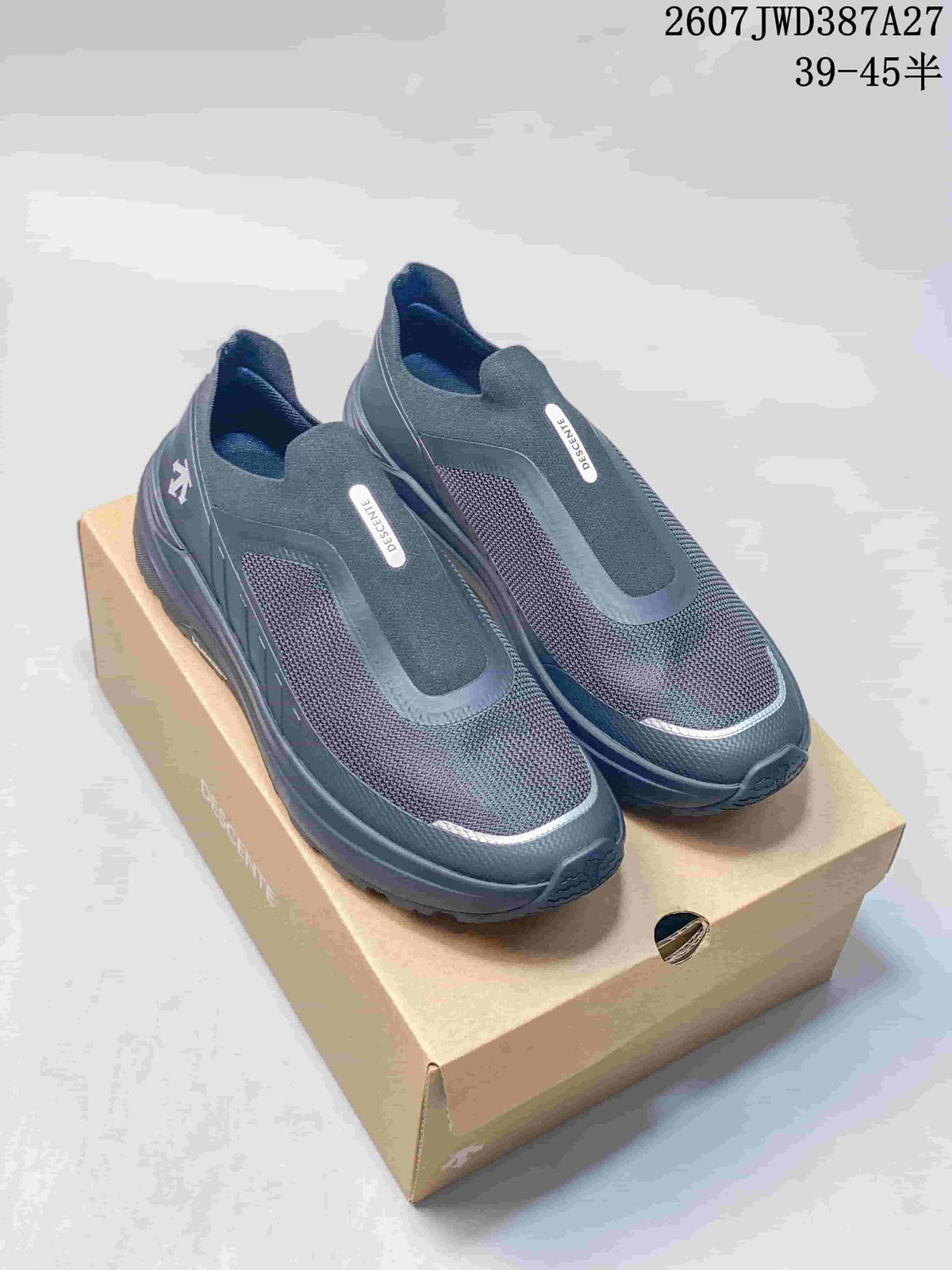 Pair of dark gray DESCENTE PRIMER slip-on sneakers displayed on a shoebox, with the style code and size range shown above.