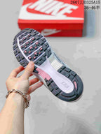Close-up of the sneaker outsole showing segmented black tread with pink accents and a central Nike-marked section.