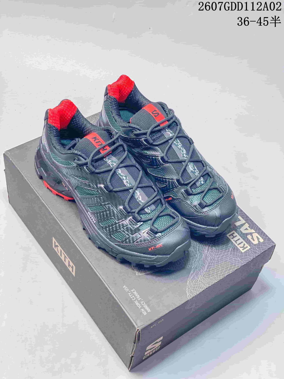 Pair of dark navy Salomon XT-4K sneakers with red accents, shown on a box.