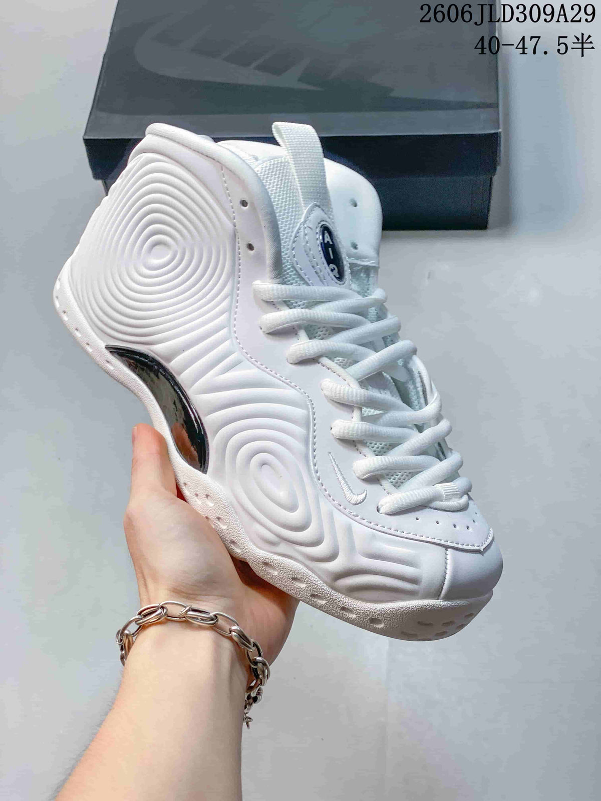Angled side view of a white high-top sneaker with a dark glossy side insert and sculpted upper.