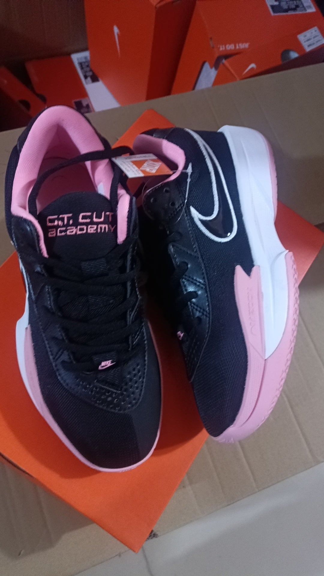 Black Nike Court Academy sneakers with pink accents and a white-and-pink sole, photographed from above