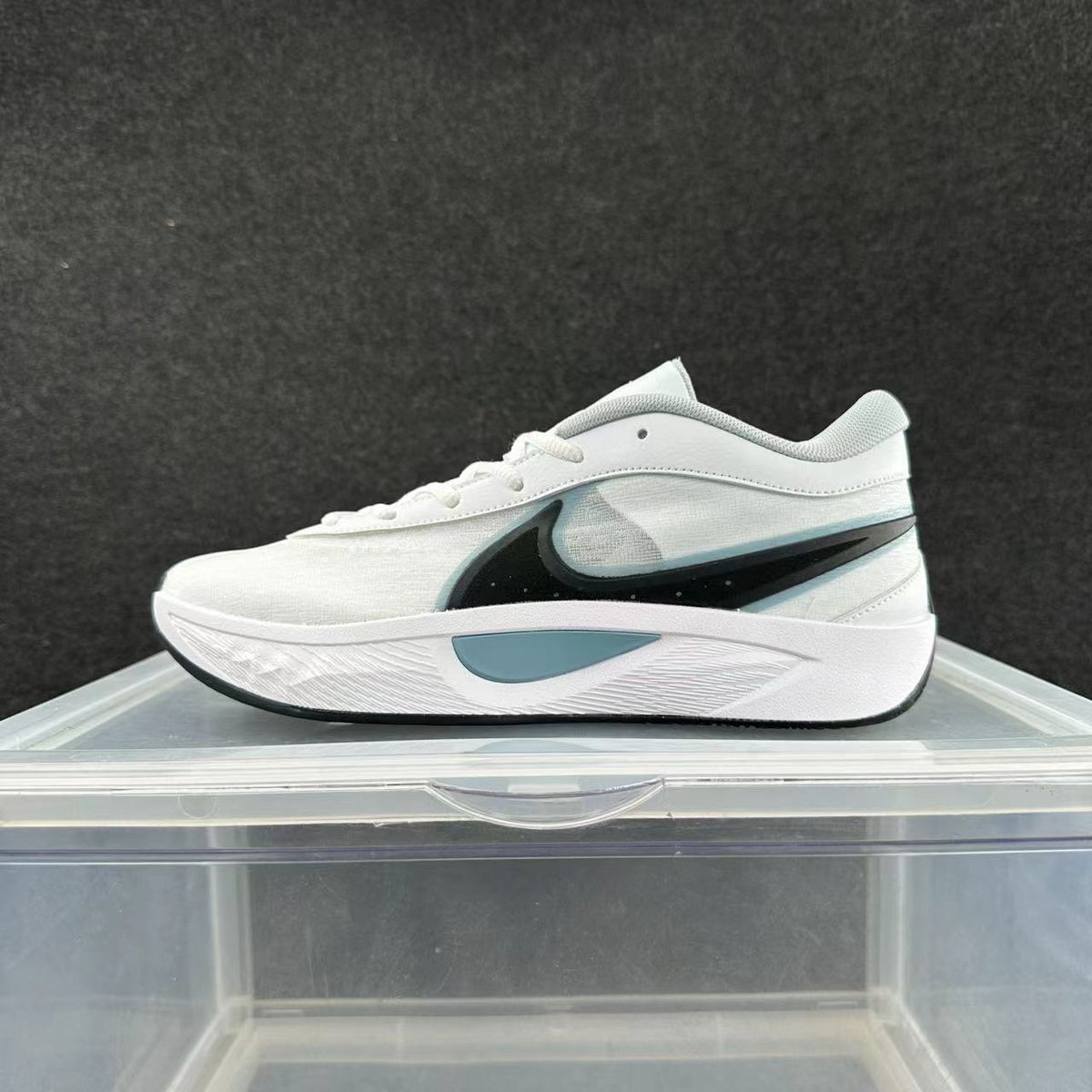 Side view of a white Nike sneaker with a black Swoosh and pale blue-gray midsole accent.