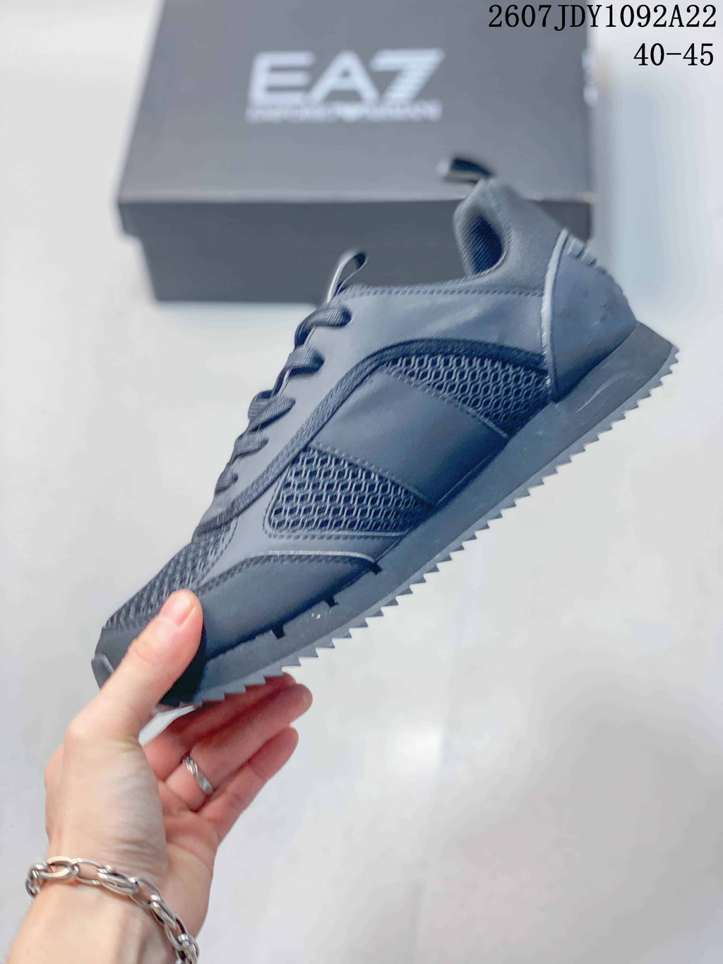 Side profile of a dark gray EA7 sneaker showing mesh-style panels, layered trim, laces, and a ridged outsole; image text shows JDY1092A22 and 40–45.