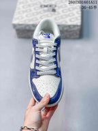 Top view showing white perforated toe panels, blue overlays, gray and white laces, and tongue branding.