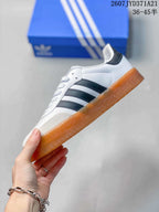 Side profile showing the white upper, black contrast stripes, and gum-colored sole.