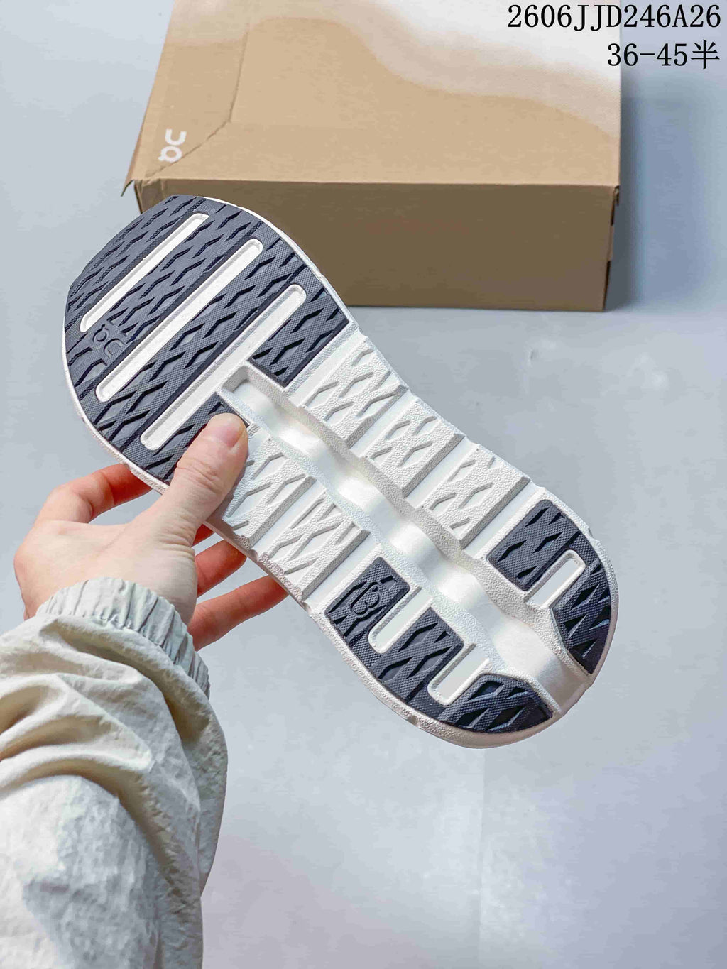 Close view of the sneaker outsole showing dark traction sections and a sculpted white sole.