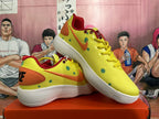 Angled view of the pair highlighting the yellow uppers, orange Swoosh branding, green dots, red collar, and white soles.
