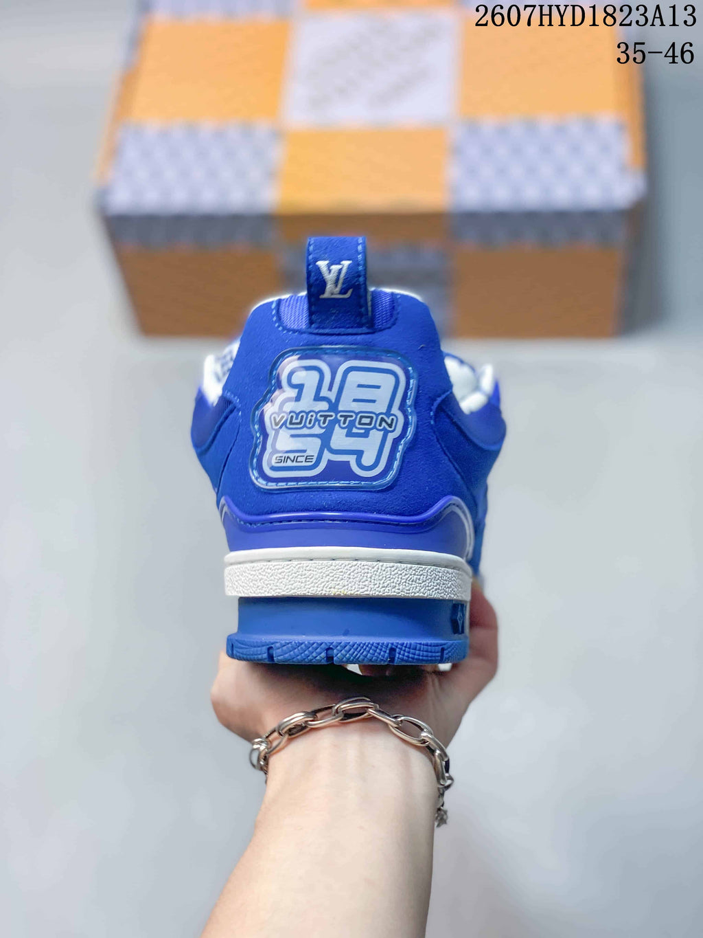 Rear view of a blue Louis Vuitton Trainer sneaker showing the branded heel panel, white midsole, and blue outsole.