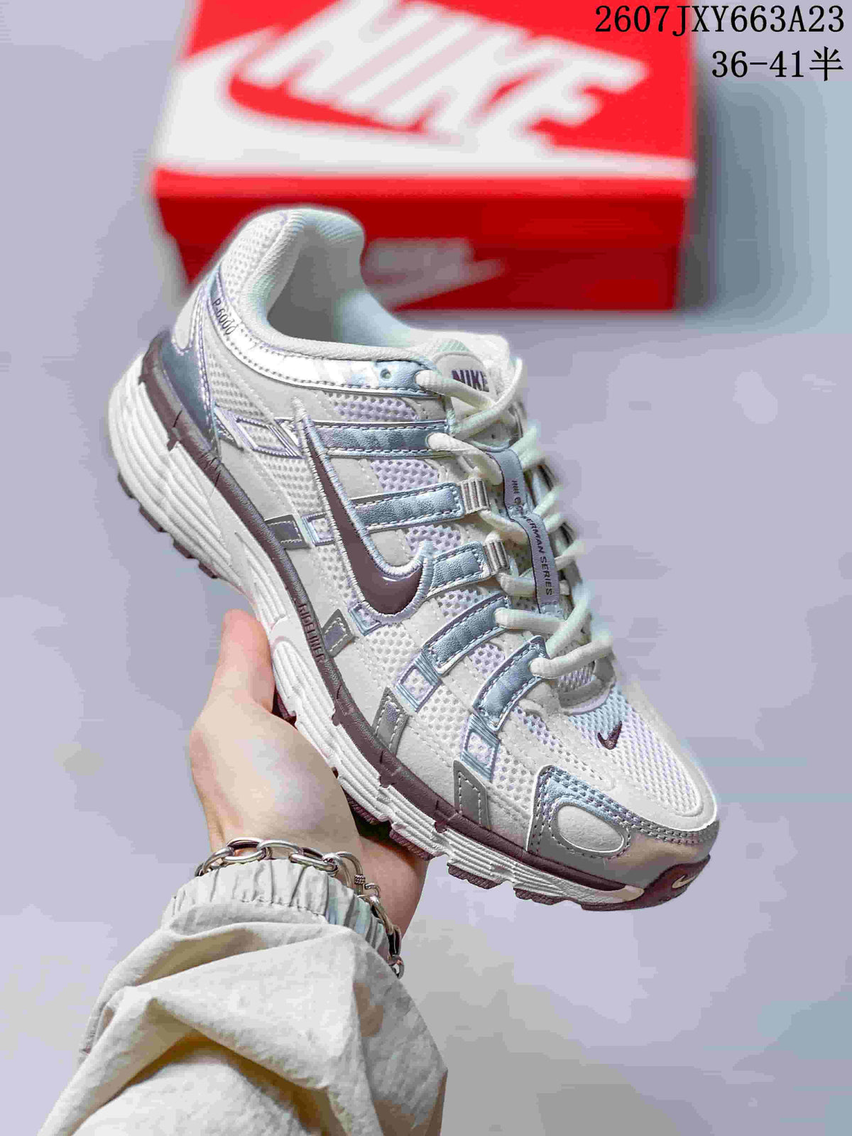 Angled side view of the white and silver Nike P-6000 sneaker in hand.