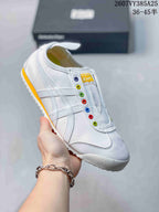 White slip-on sneaker with colorful eyelets, white side stripes and a yellow outsole accent.