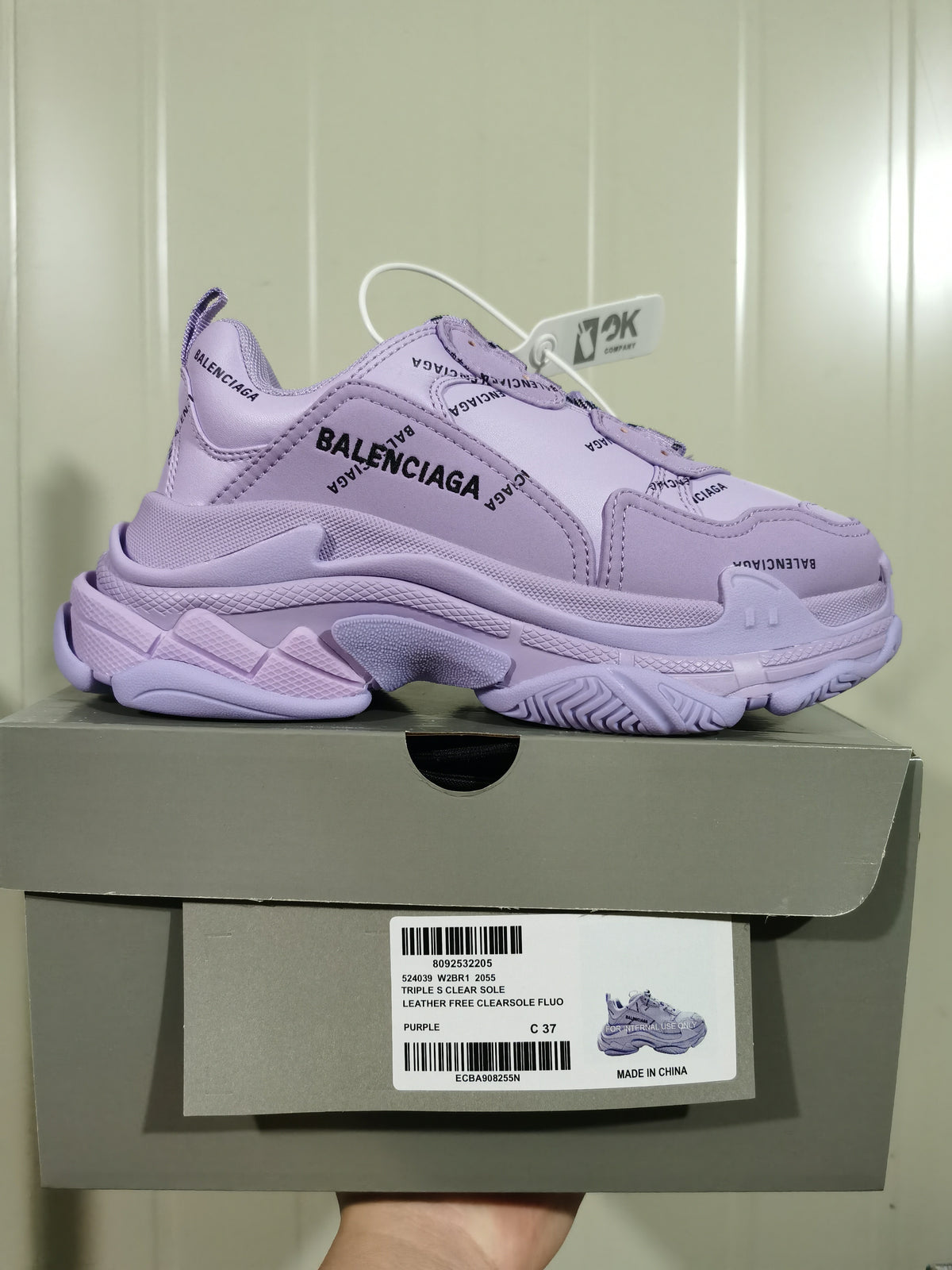 Purple Balenciaga Triple S sneaker positioned on its shoebox, with the product label visible.