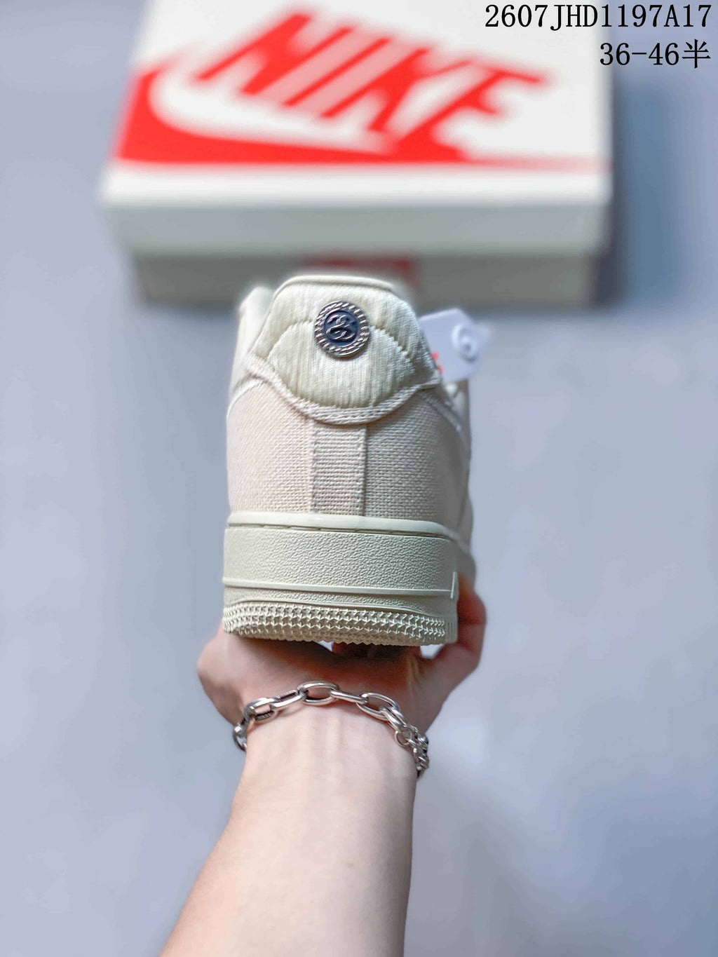 Rear view of the cream sneaker showing the heel panel, tonal stitching, and circular Stussy detail.