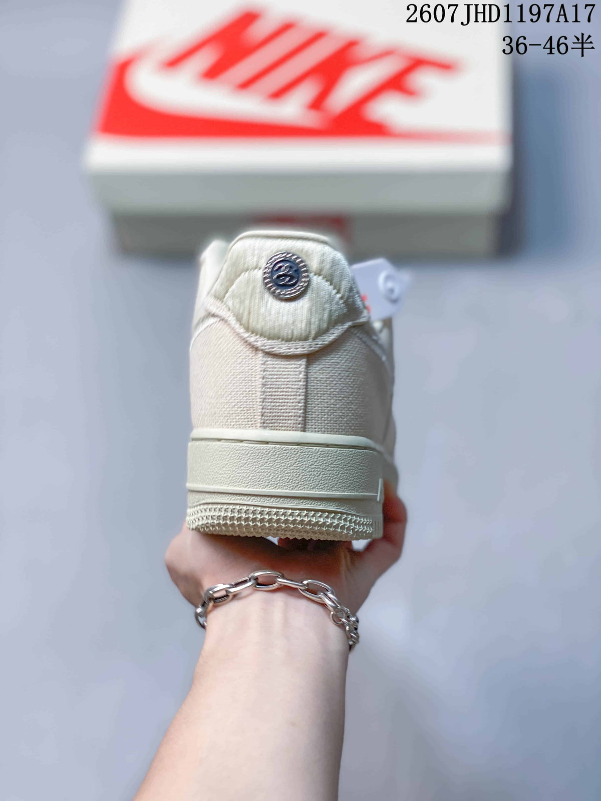 Rear view of the cream sneaker showing the heel panel, tonal stitching, and circular Stussy detail.