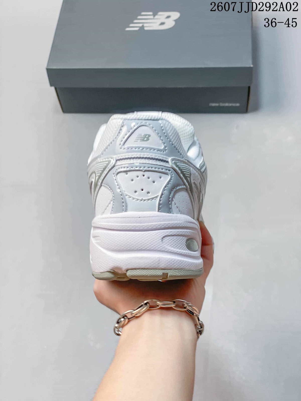 Rear view of the white and grey New Balance 509 sneaker showing the padded heel area and layered heel construction.