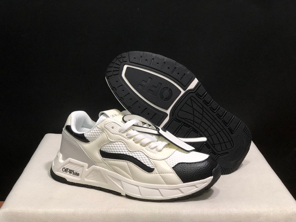 Angled view of the sneakers with one shoe lifted to show the black patterned outsole.