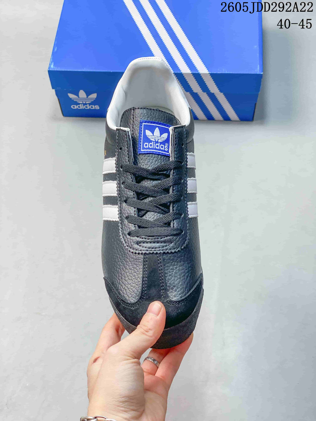 Top view of a dark gray adidas Samoa sneaker showing the white lining, blue tongue label, and black laces.