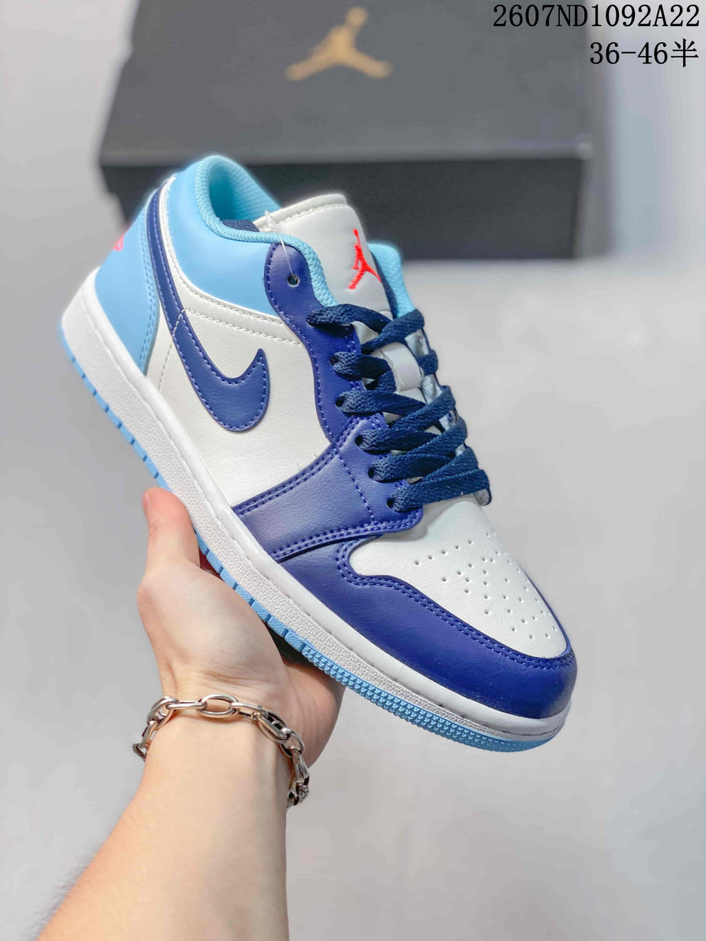 White, light blue, and royal blue low-top Jordan sneaker with red tongue branding.