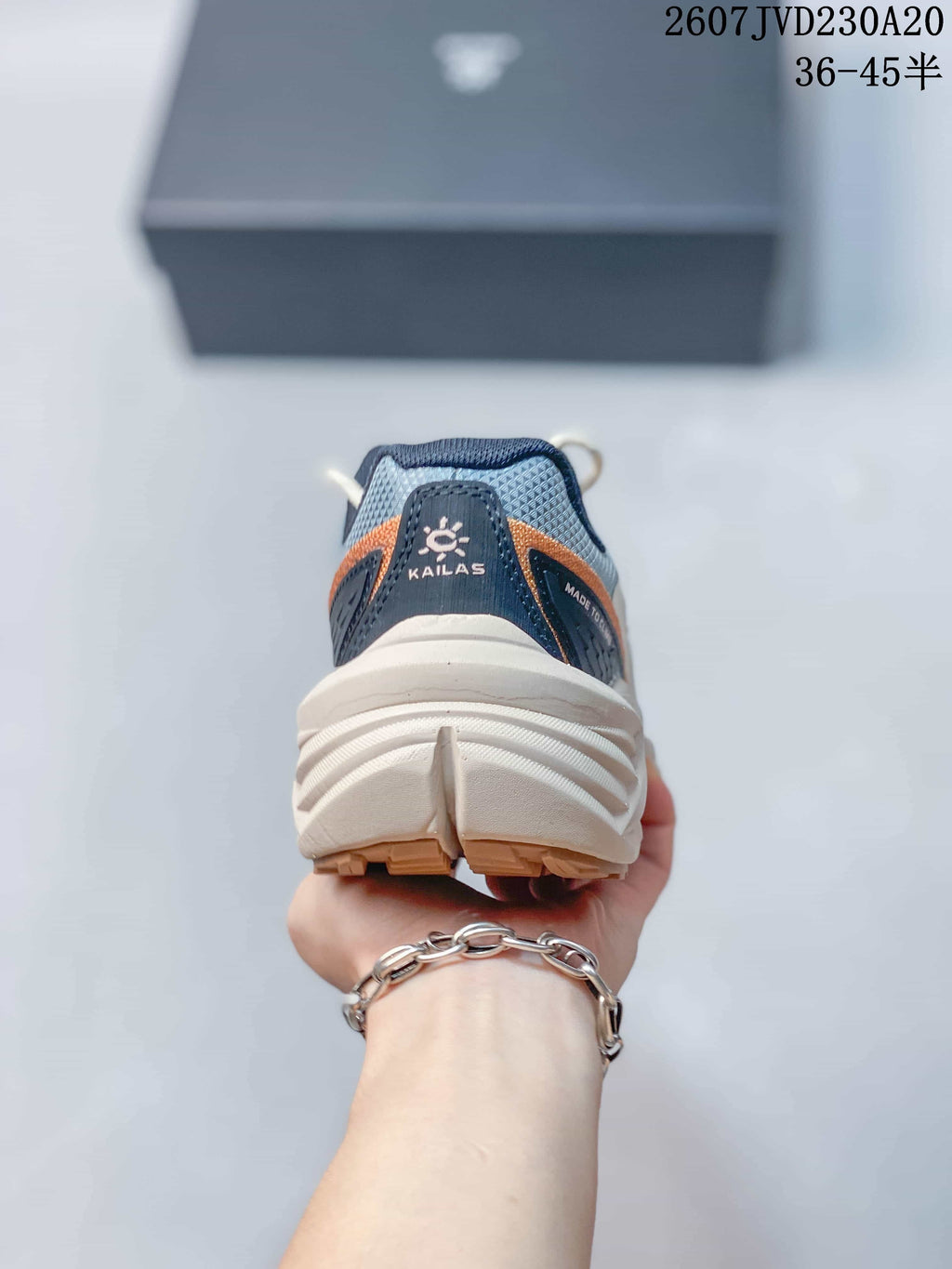 Rear view showing the padded navy heel collar, KAILAS branding, orange detailing, and layered off-white sole.