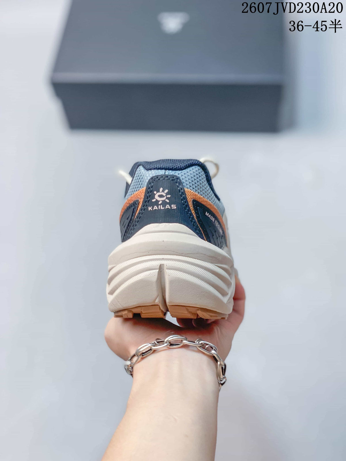 Rear view showing the padded navy heel collar, KAILAS branding, orange detailing, and layered off-white sole.