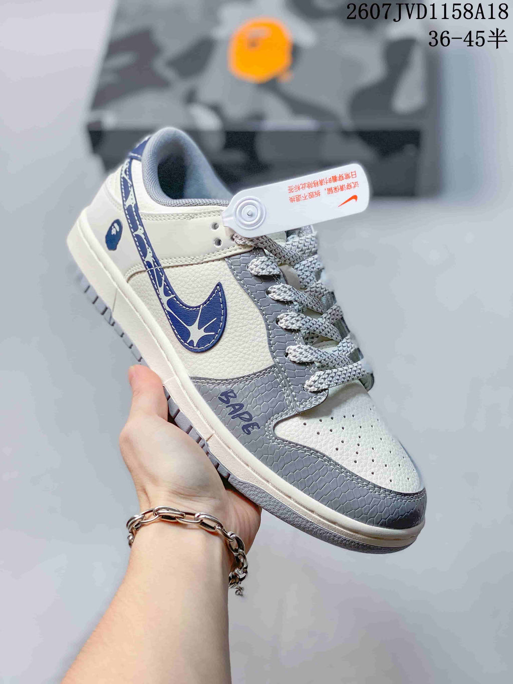 Close view of a white and gray sneaker with blue graphic Swoosh details, patterned laces, and a textured gray toe overlay.