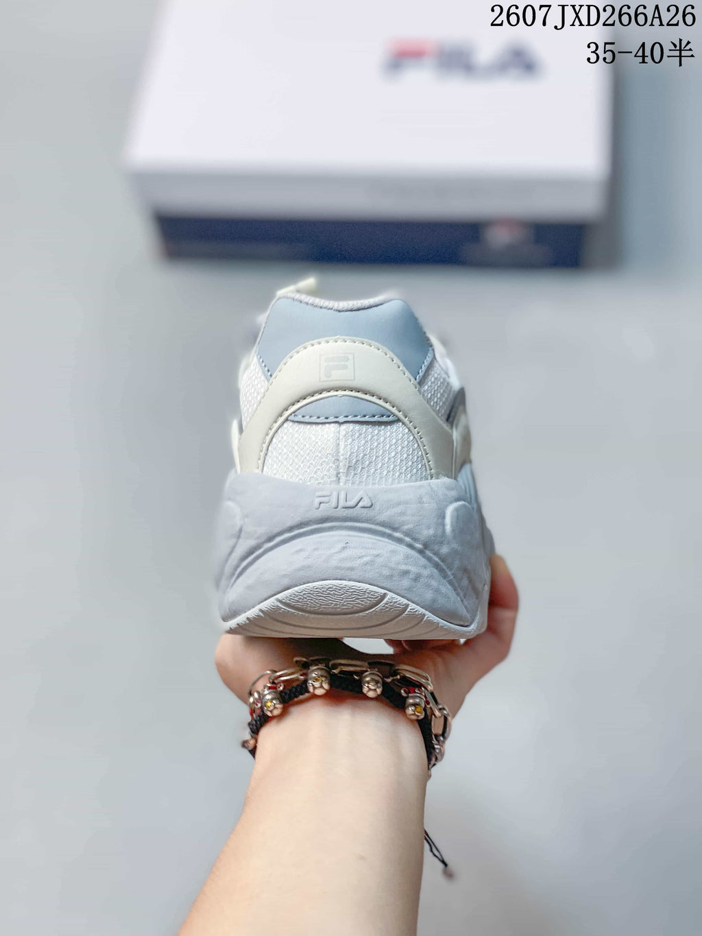 Rear view of the white and gray sneaker showing the padded heel, mesh panel, and FILA branding.