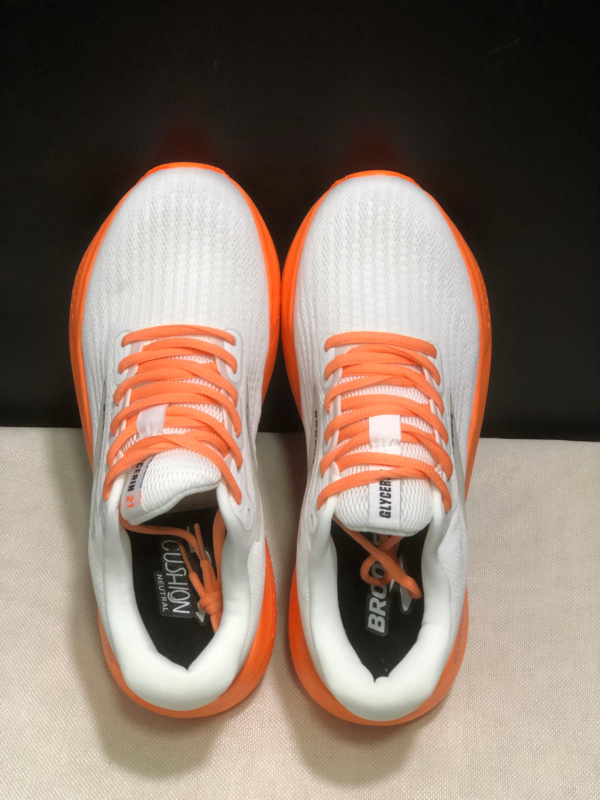 Top view showing the white textured uppers, orange laces, padded collars, and branded insoles.