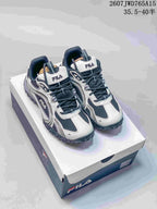 Pair of black-and-white FILA Pebble sneakers displayed on a FILA shoebox; overlay shows style code 2607JWD765A15 and size range 35.5–40.5.