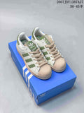 Pair of white adidas Superstar sneakers with green striped detailing, beige shell toes, beige laces, and a blue adidas shoebox; image text shows JDY1387A27 and sizes 36–45.