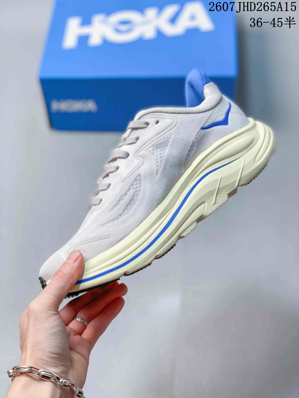 Side view of a light-colored HOKA Clifton 10 sneaker with blue accents and a layered midsole.