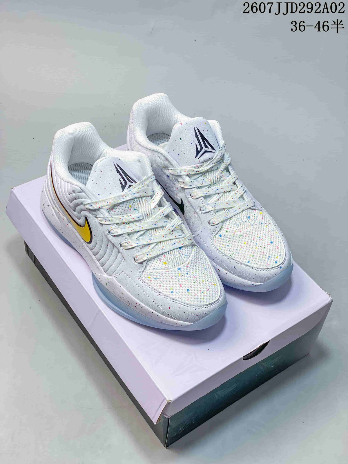 Pair of white Nike JA 2 EP basketball shoes with multicolor speckling, yellow side accents, and a shoe box behind them.