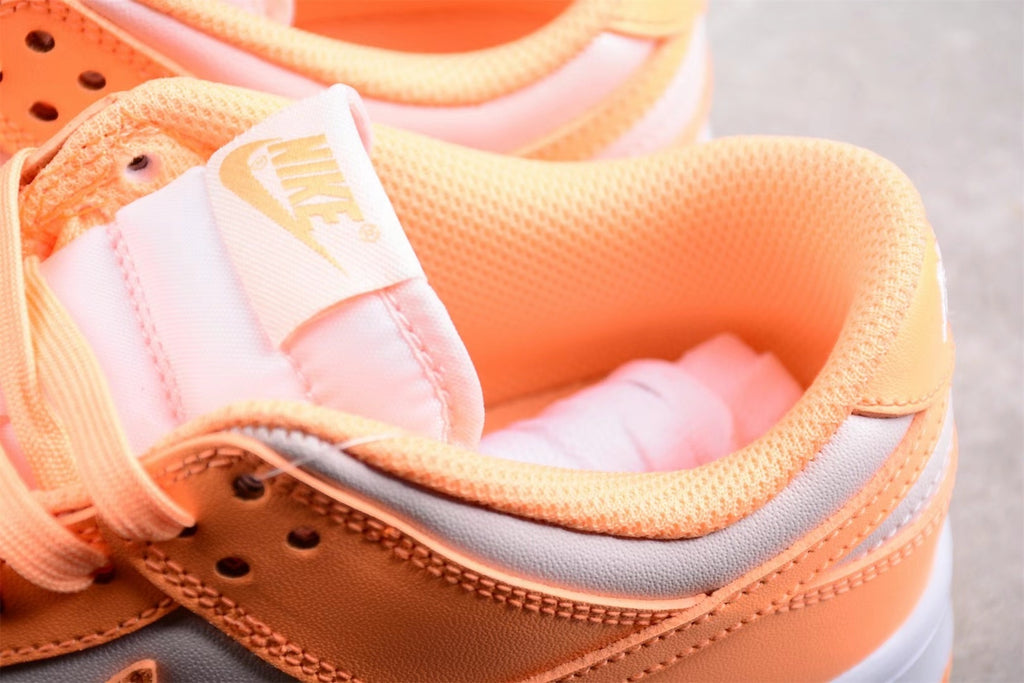 Close-up of the padded orange collar, tongue label, laces, and light gray side panel.