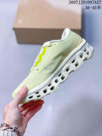 Side profile of the pale green sneaker showing the grey On logo, lace area and open-section outsole.
