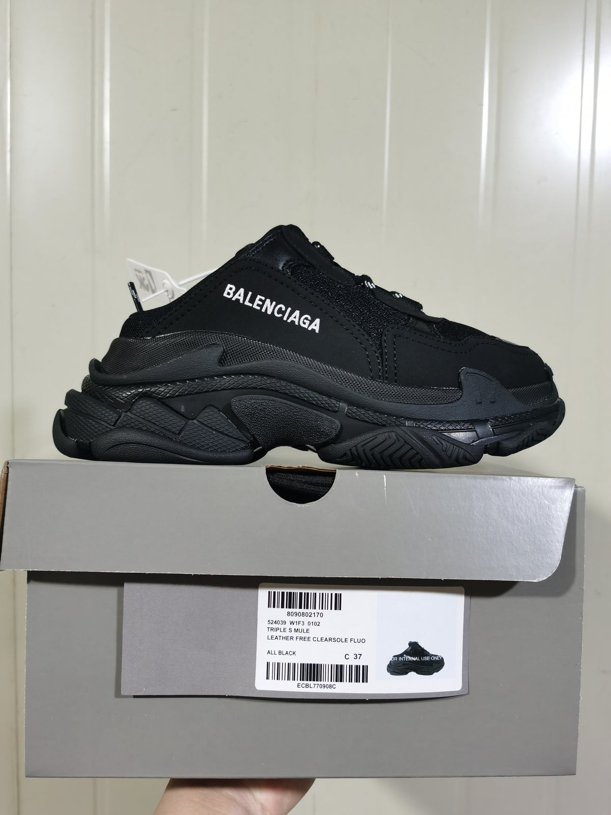 Black Balenciaga sneaker displayed on its box; the visible label reads Triple S Mule, All Black, leather free, and size C 37.