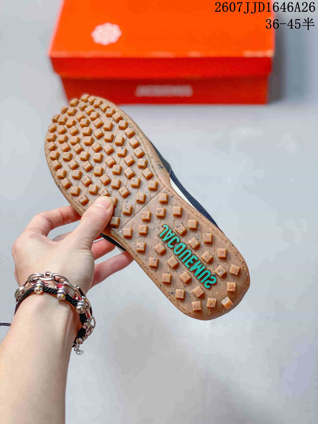 Underside view showing the gum-colored outsole with raised square tread blocks and teal lettering.