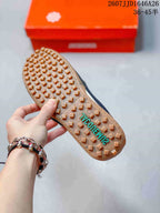Underside view showing the gum-colored outsole with raised square tread blocks and teal lettering.