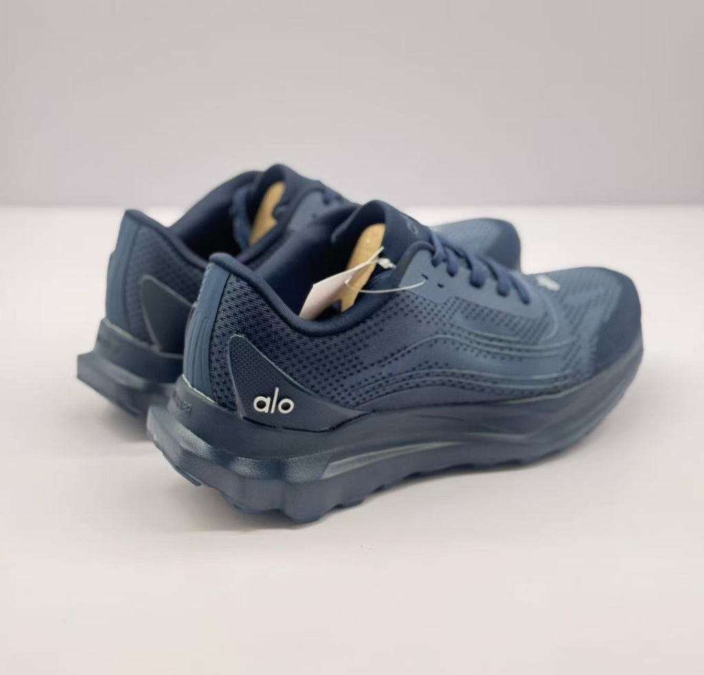 Rear three-quarter view of the dark blue Alo sneakers showing the heel branding and raised sole structure.