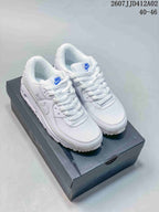 Pair of white Nike Air Max 90 sneakers with blue accents on a dark shoebox