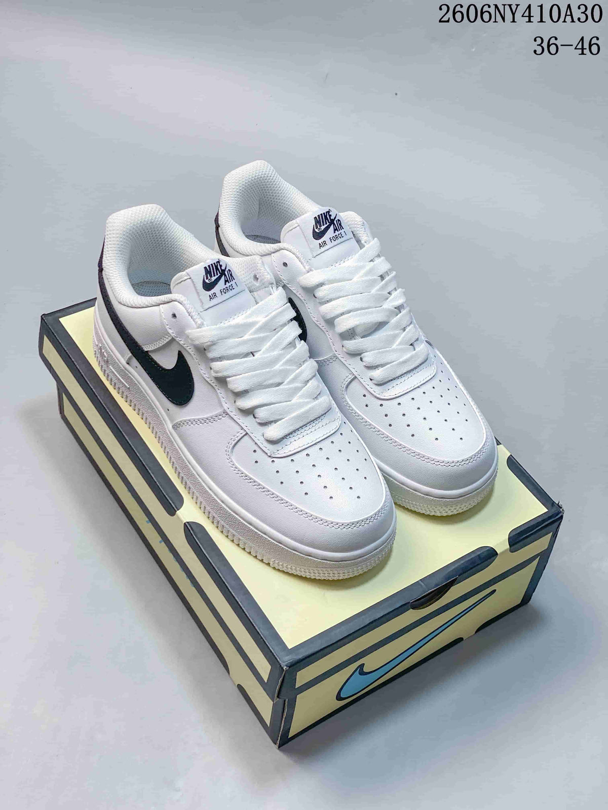 Pair of white Nike Air Force 1 low-top sneakers with navy Swooshes on a shoe box