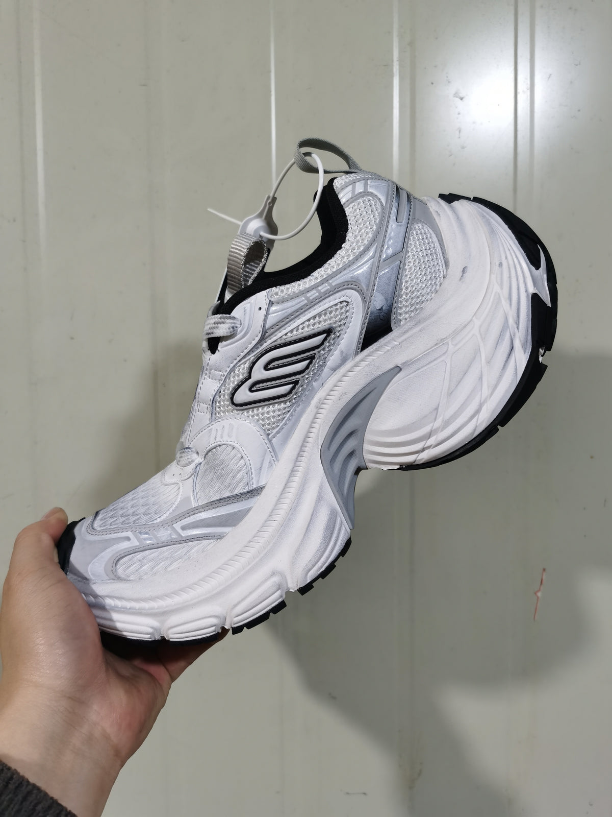 Side and rear angled view of the white and black 9110 sneaker showing the mesh upper, sculpted sole, and black outsole.